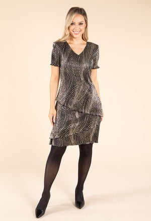 model wearing black and gold dress on beige background