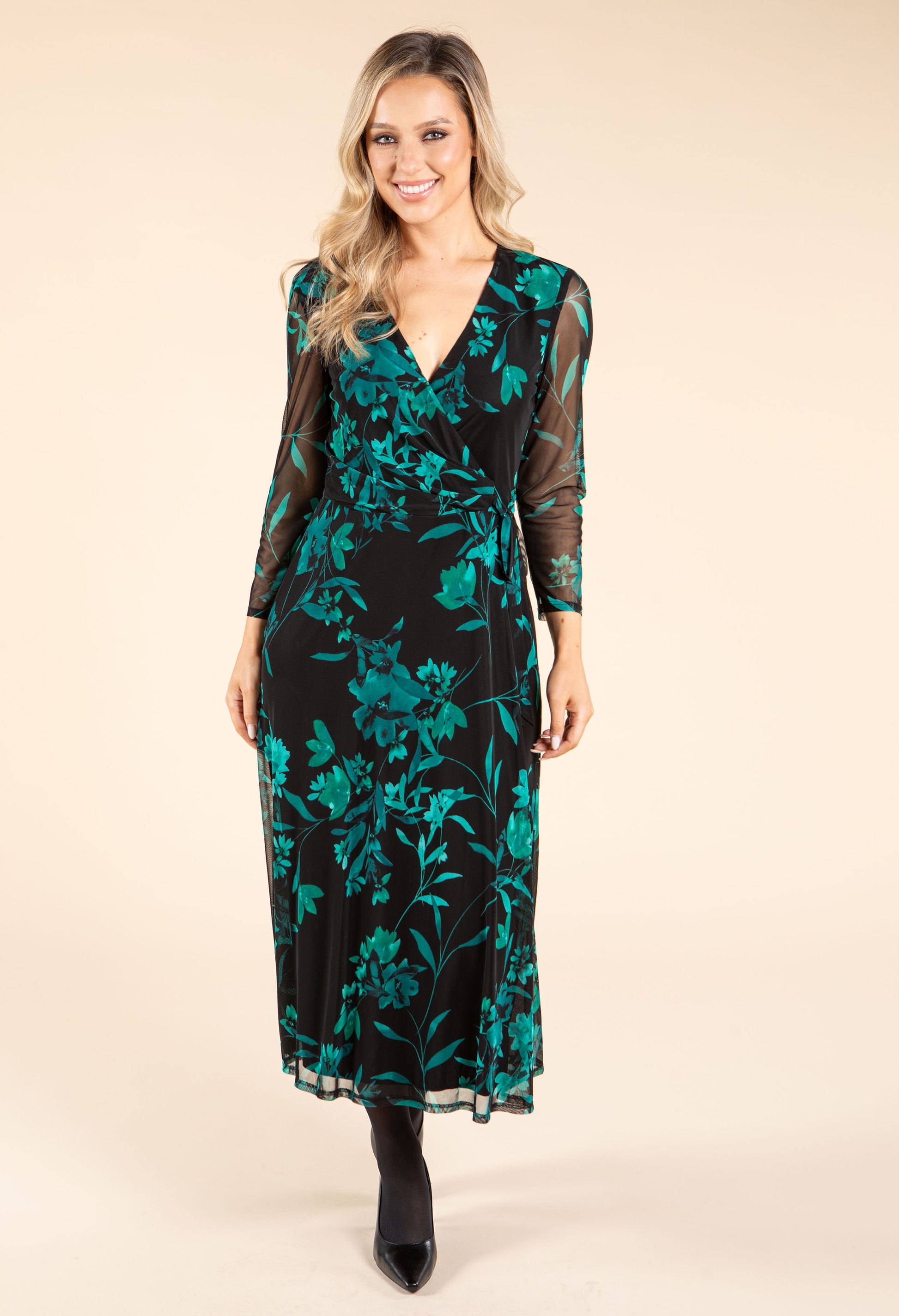 Woman wearing a black dress with green floral pattern on a beige background