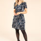 model wearing a navy plisse printed dress on a beige background