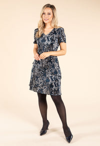 model wearing a navy plisse printed dress on a beige background