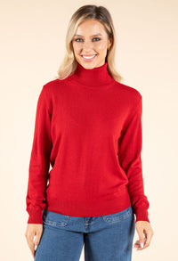 Woman wearing a red turtleneck sweater and blue jeans on a beige background