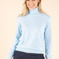 Woman wearing a light blue turtleneck sweater against a beige background