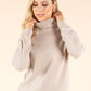 Woman wearing a beige turtleneck sweater against a beige background