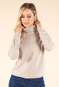 Woman wearing a beige turtleneck sweater against a beige background