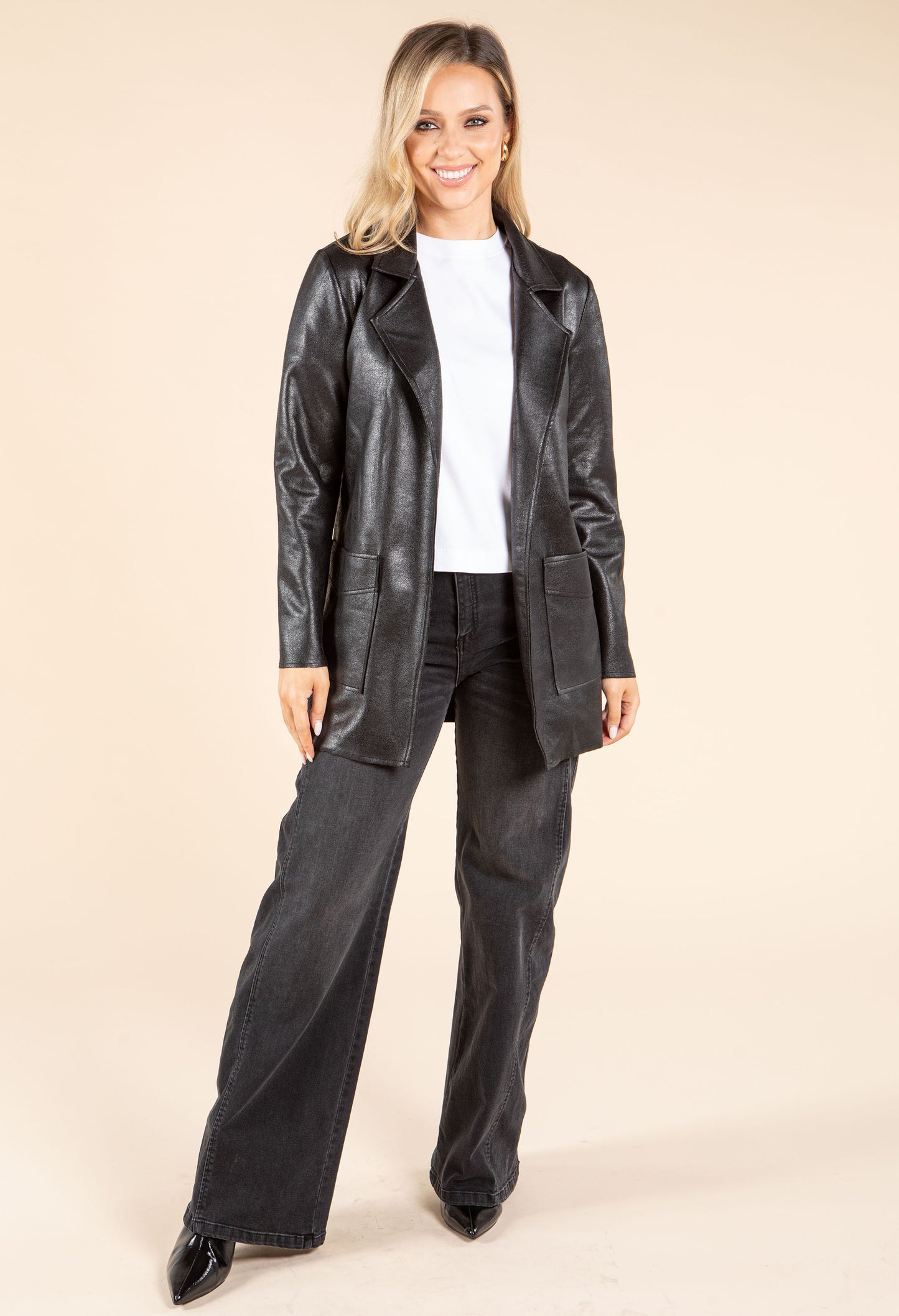 Woman wearing a black leather jacket and pants on a beige background