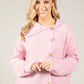Woman wearing a pink textured cardigan with a neutral background