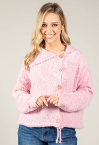 Woman wearing a pink textured cardigan with a neutral background