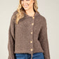Woman wearing a brown textured cardigan with buttons against a plain background