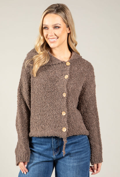 Woman wearing a brown textured cardigan with buttons against a plain background