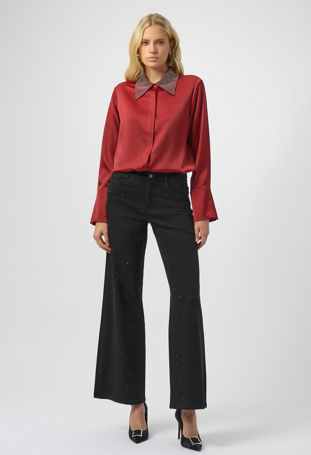 Woman wearing a red blouse with a brown collar and black pants on a white background
