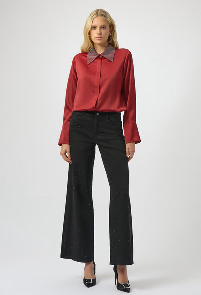 Woman wearing a red blouse with a brown collar and black pants on a white background