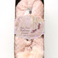 Pink pom-pom ballerina shoes in packaging with a decorative label on a white background