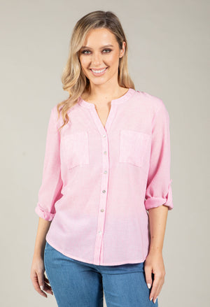 Woman wearing a pink blouse and blue jeans on a plain background