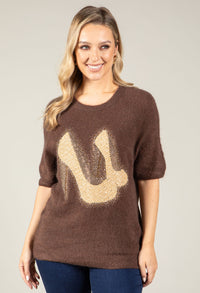 Woman wearing a brown sweater with a large beige 'U' design on a plain background