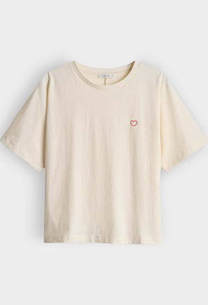 Beige t-shirt with a small red heart on a light gray background