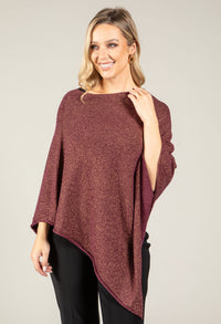 Woman wearing a burgundy poncho against a plain background