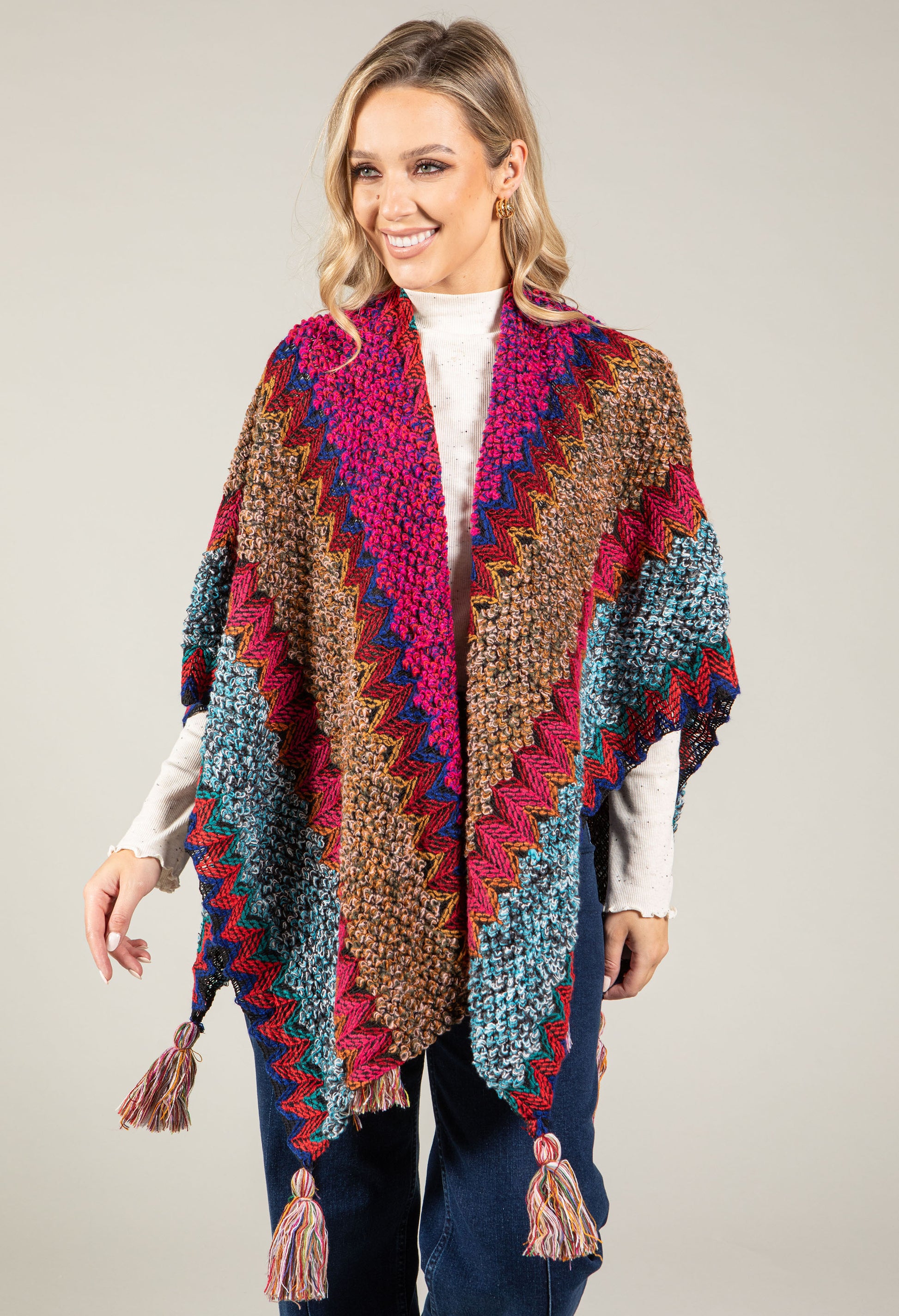 Woman wearing a colorful crocheted poncho against a plain background