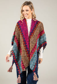 Woman wearing a colorful crocheted poncho against a plain background