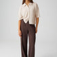 Woman wearing a beige blouse and brown pants on a white background