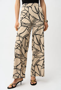 Beige pants with black abstract pattern worn by a person on a white background