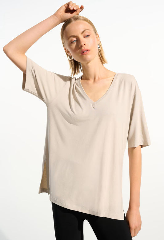 Woman wearing a black V-neck top and blue pants on a white background