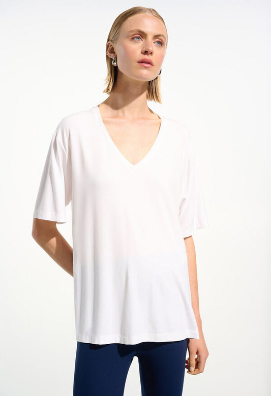 Woman wearing a black V-neck top and blue pants on a white background