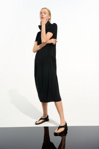 Woman wearing a black dress standing against a white background