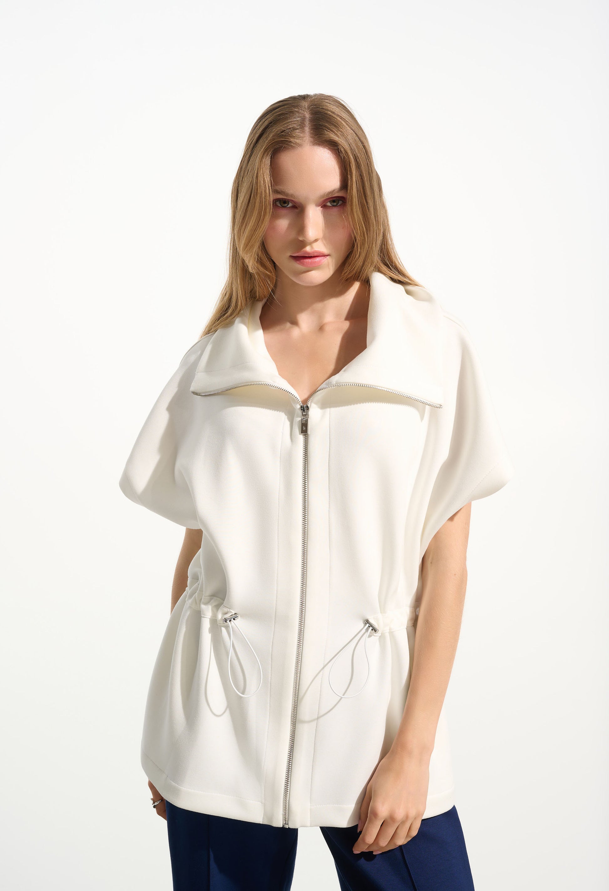Woman wearing a white zip-up jacket on a white background