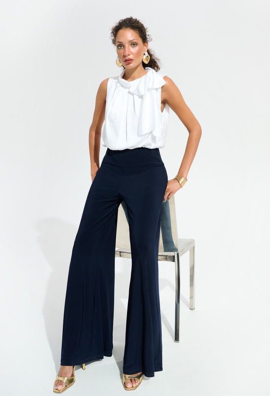 Woman wearing a white blouse and navy pants on a white background