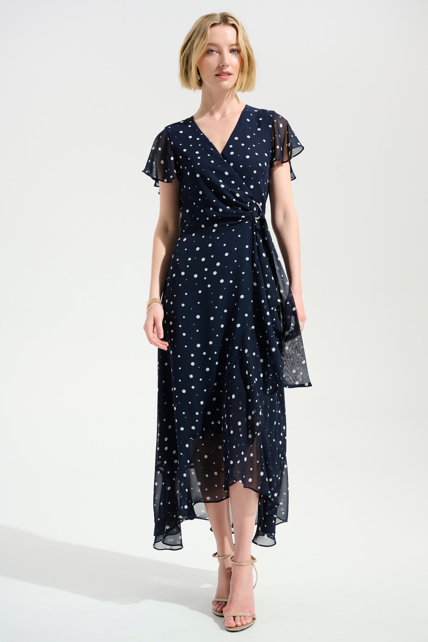 Woman wearing a navy dress with white polka dots on a white background