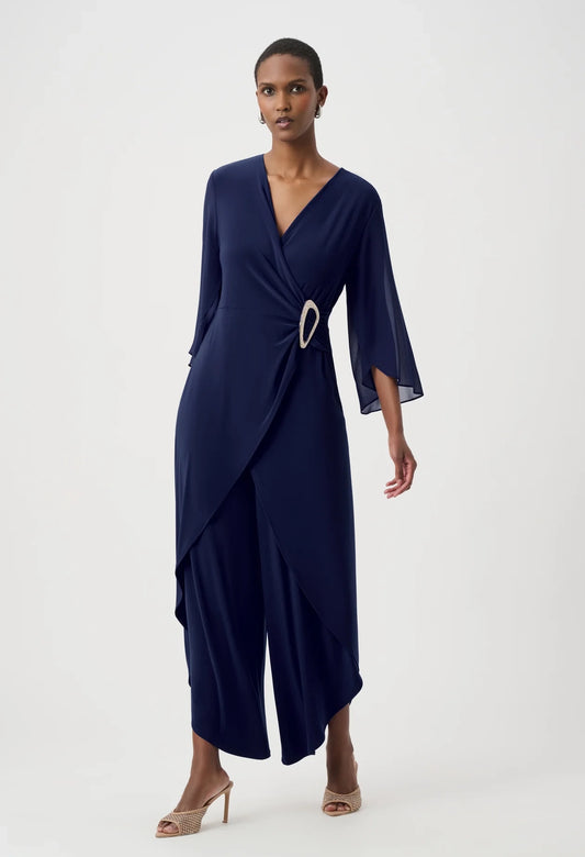 woman wearing a coral wrap style jumpsuit on a white background