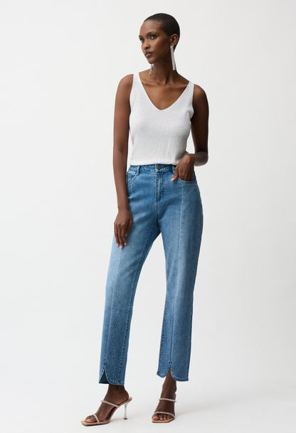 Woman wearing a white tank top and blue jeans on a white background