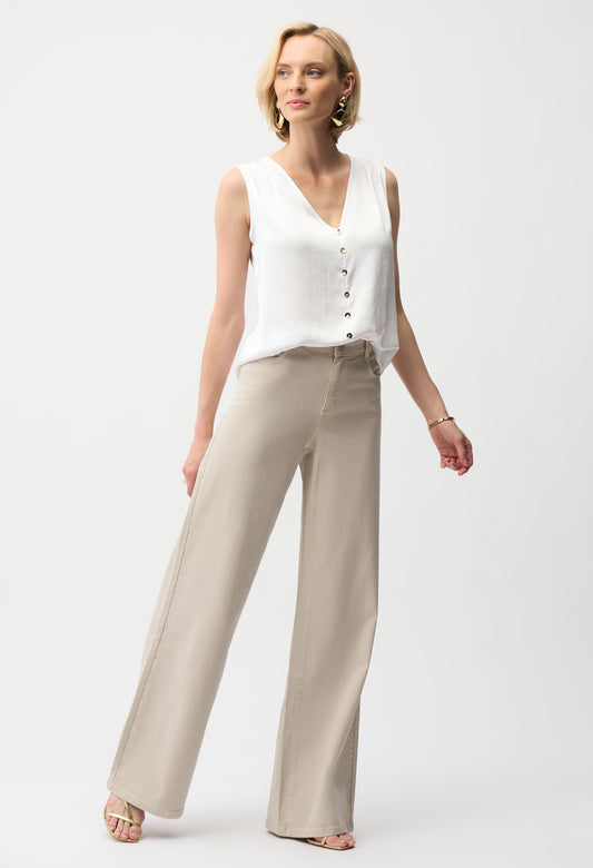 Woman wearing a white sleeveless top and beige pants on a white background