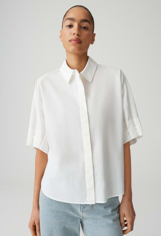 Person wearing a white shirt and light blue jeans against a plain background