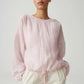 Person wearing a light pink blouse with long sleeves on a plain background