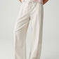 Person wearing light pink top and beige wide-leg pants on a white background