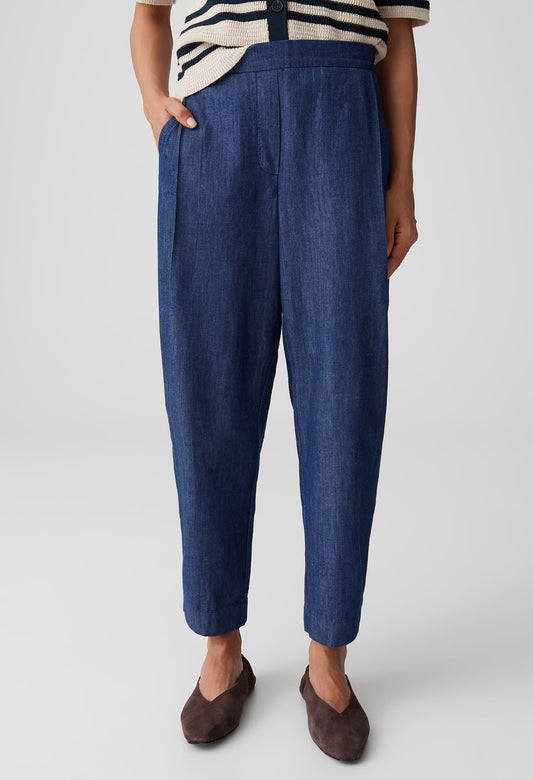 Person wearing blue pants and a striped shirt on a plain background