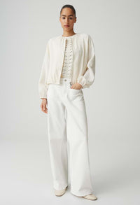 Person wearing a white outfit with a jacket and pants on a plain background