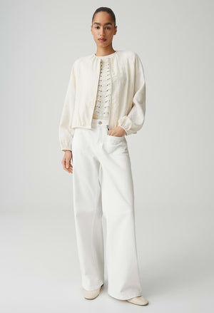 Person wearing a white outfit with a jacket and pants on a plain background
