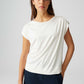 Woman wearing a white top and navy pants on a light gray background