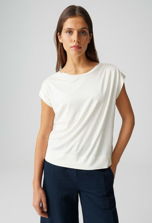 Woman wearing a white top and navy pants on a light gray background