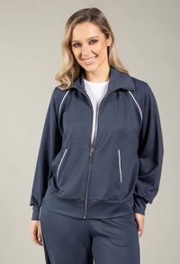 Woman wearing a navy tracksuit with white accents on a beige background
