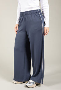 Person wearing blue wide-leg pants with a white shirt on a plain background