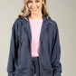 Woman wearing a navy blue tracksuit with a pink top on a gray background