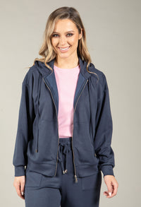 Woman wearing a navy blue tracksuit with a pink top on a gray background