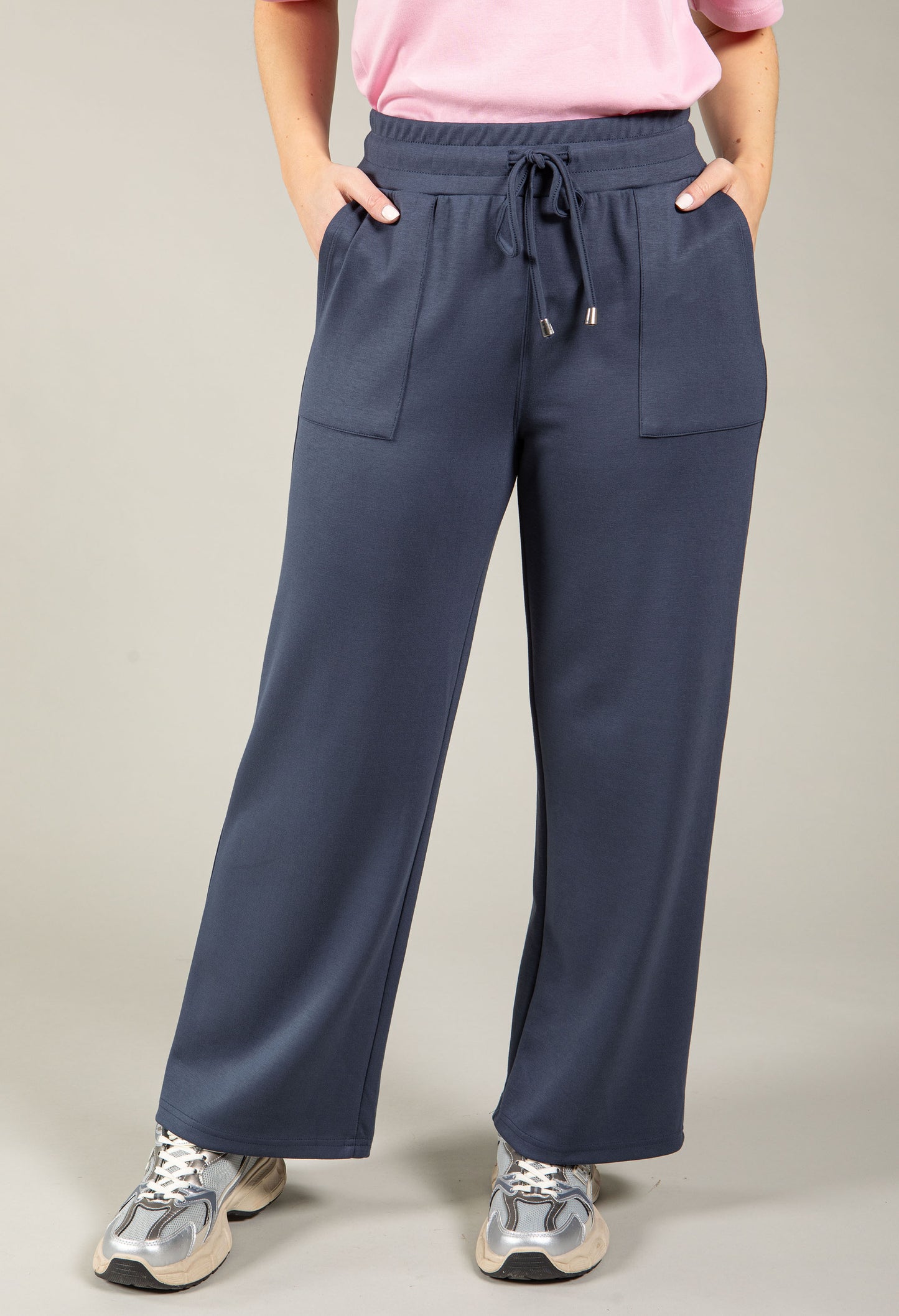 Person wearing navy blue drawstring pants on a plain background