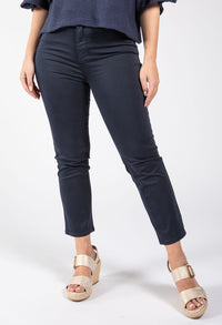 Person wearing navy blue pants and gold sandals on a white background