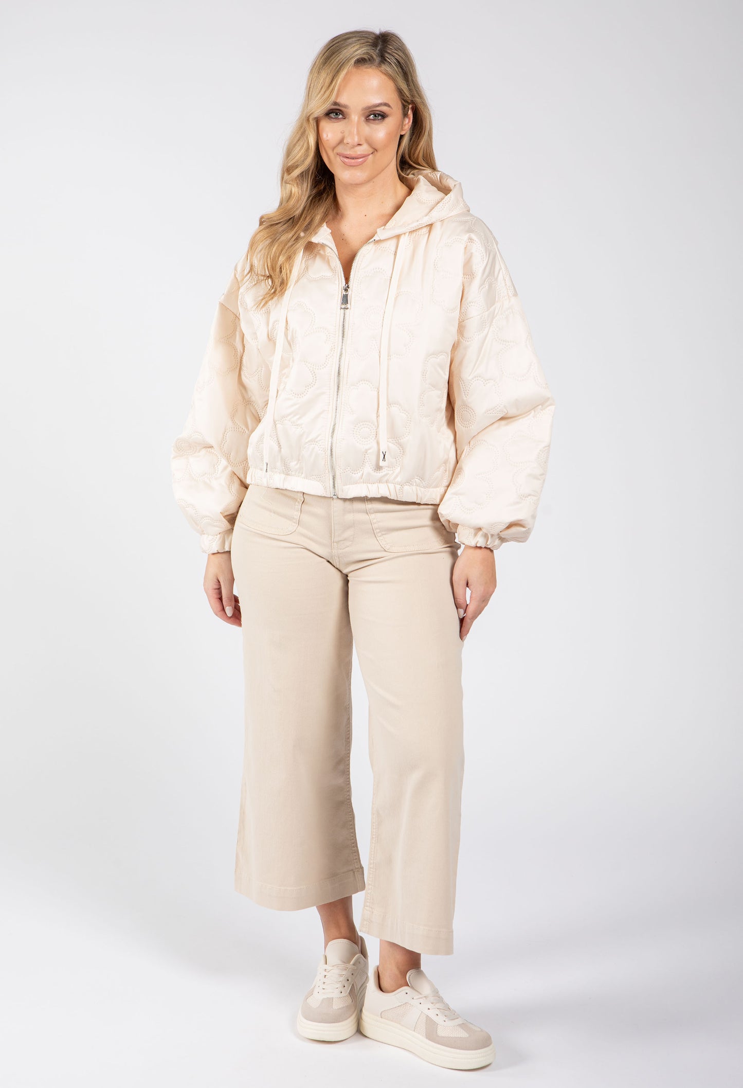 Woman wearing a beige jacket and pants on a white background