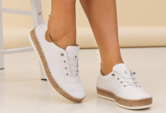 White sneakers with cork soles worn by a person on a light background