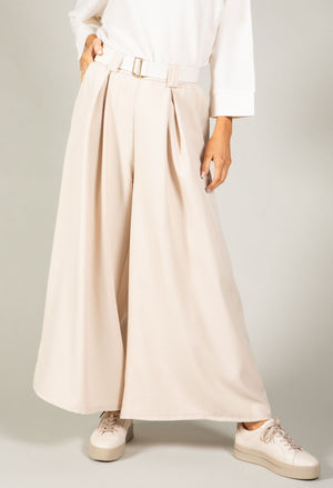 Person wearing a white shirt and beige wide-leg pants on a plain background